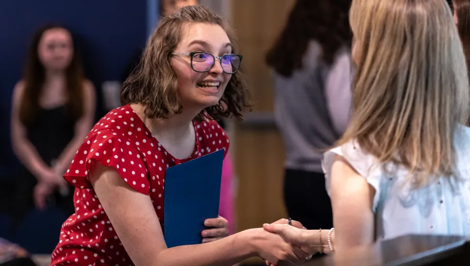 A student shakes a PSI CHI officer's hand