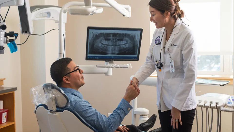 Female dental school student shakes hand with patient at UNE dental school's clinic in Portland, Maine.