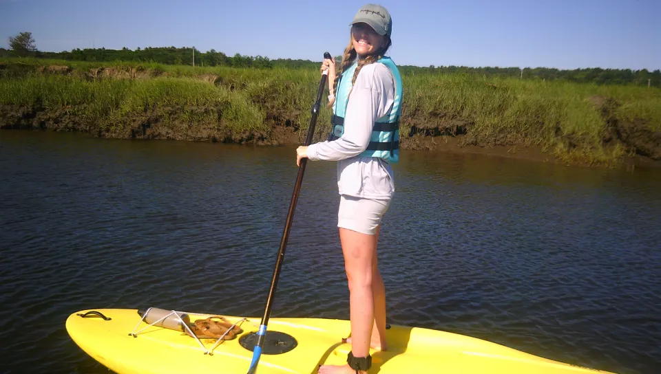 A female student navigates on a stand-up paddleboard