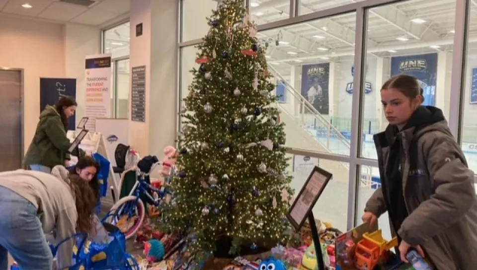 Students gather toys and gifts from the Giving Tree in the Harold Alfond Forum