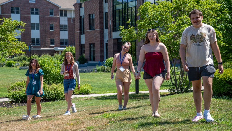Several students walk on the UNE lawn