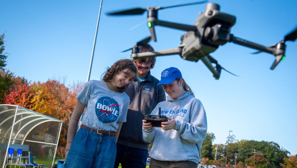 Three U N E students fly a drone