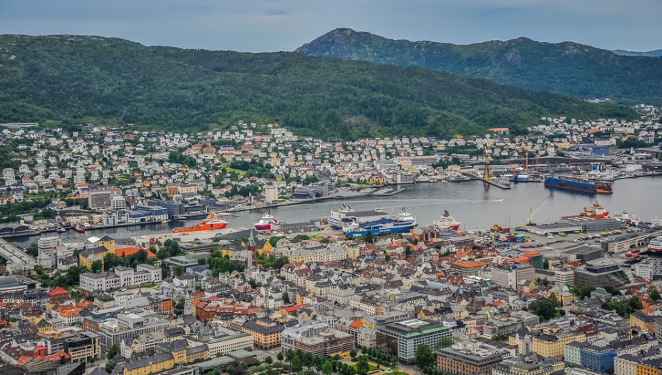 An aerial view of a colorful city on the ocean with mountains in the background