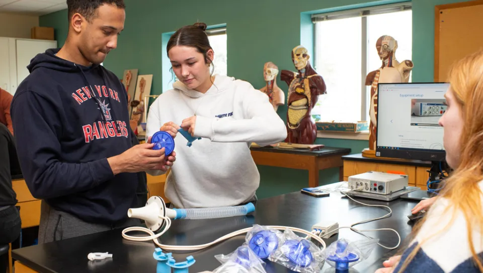 Two students prepare a medical tool for testing lung capacity