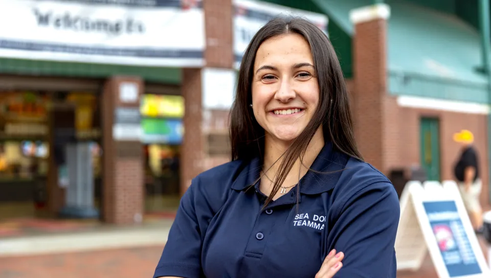 A UNE student poses in front of the Hadlock Field entrance