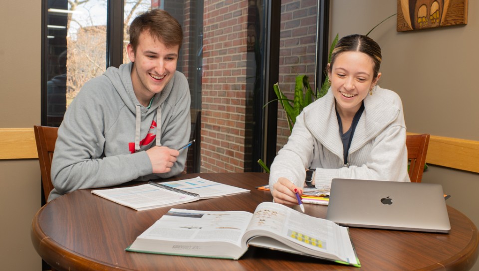 Two students studying together with an open book in front of them