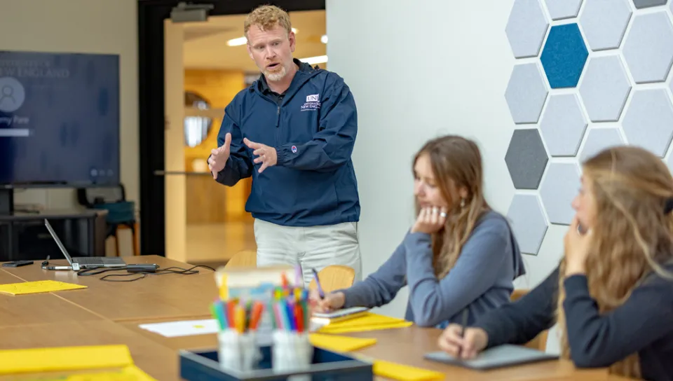 A group of students listen to a professor in a classroom