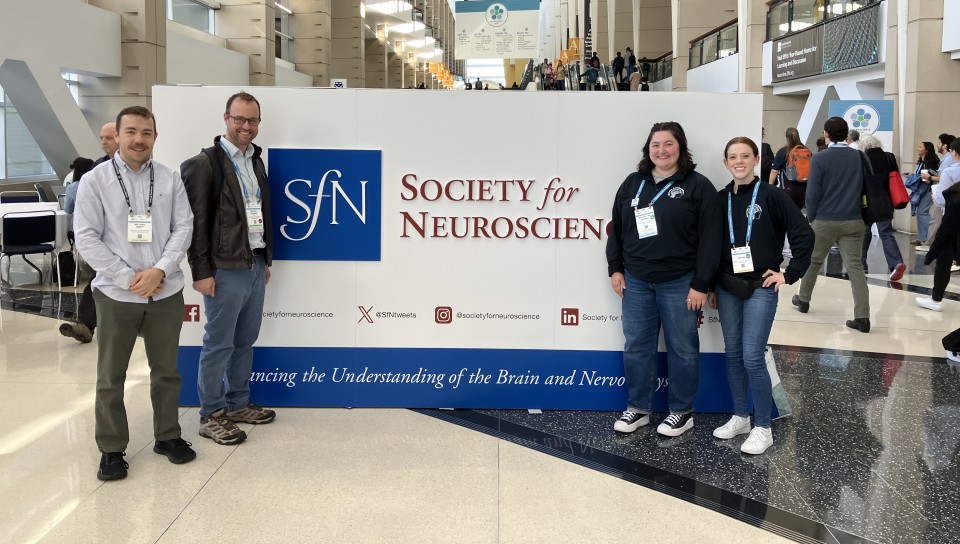 A group of UNE researchers pose in front the Society for Neuroscience sign