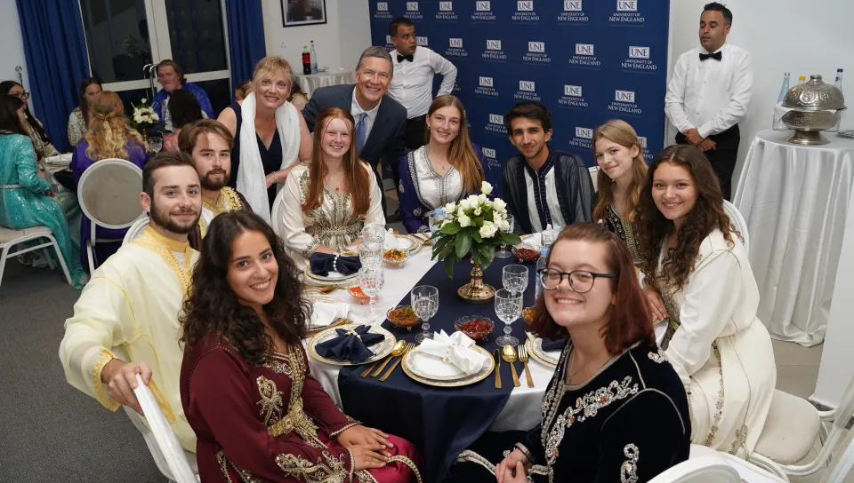 UNE students pose for a photo around a dinner table