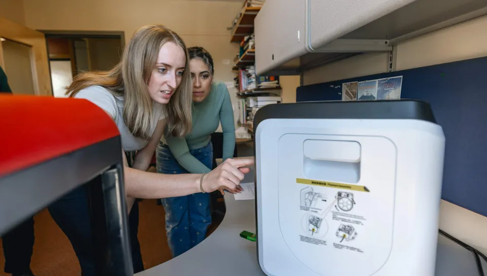 Two students operate a 3D printer