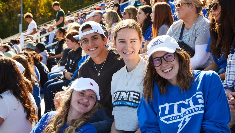 A group of UNE students poses for a photo in the stands at Homecoming