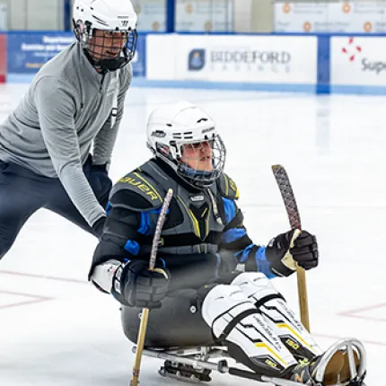 A UNE student pushes a man on a hockey sled as part of a demonstration