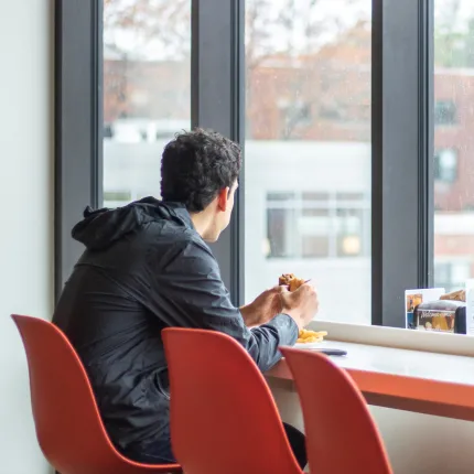 A student looks out a window in the Commons