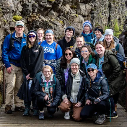 A group of U N E students taking a photo together in a rocky and mossy gorge