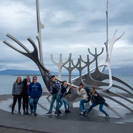 Several students stand in front of a steel sculpture of a viking ship on Reykjavik's waterfront