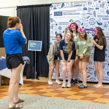 A group of students getting their photo taken in front of an illustrated background