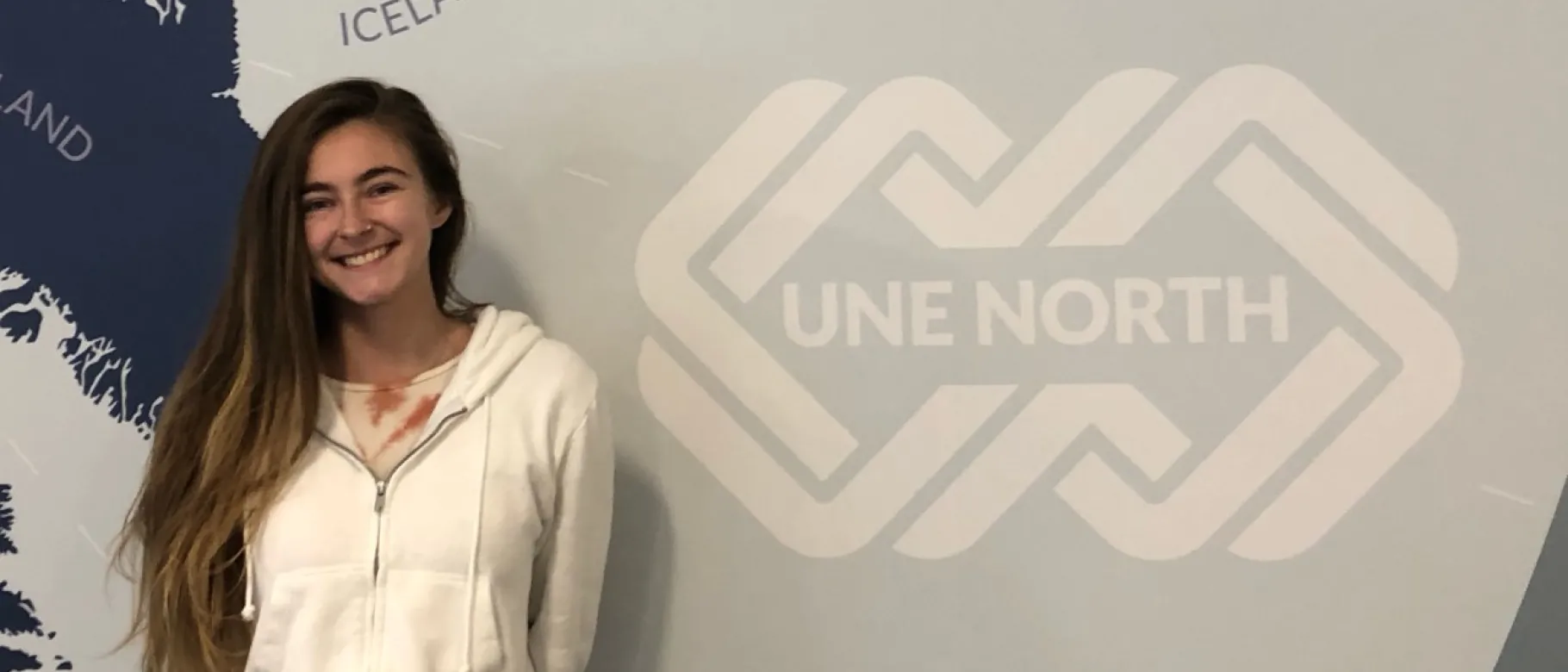 Photo of woman smiling against wall, student McKayla Arsenault