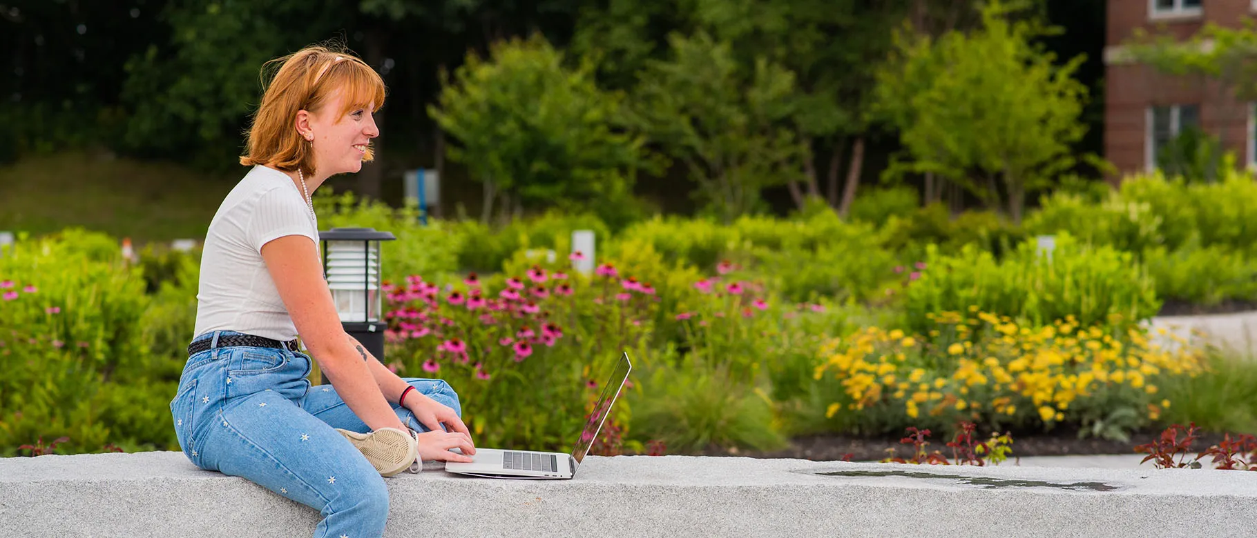 A student works on her computer outside the Ripich Commons