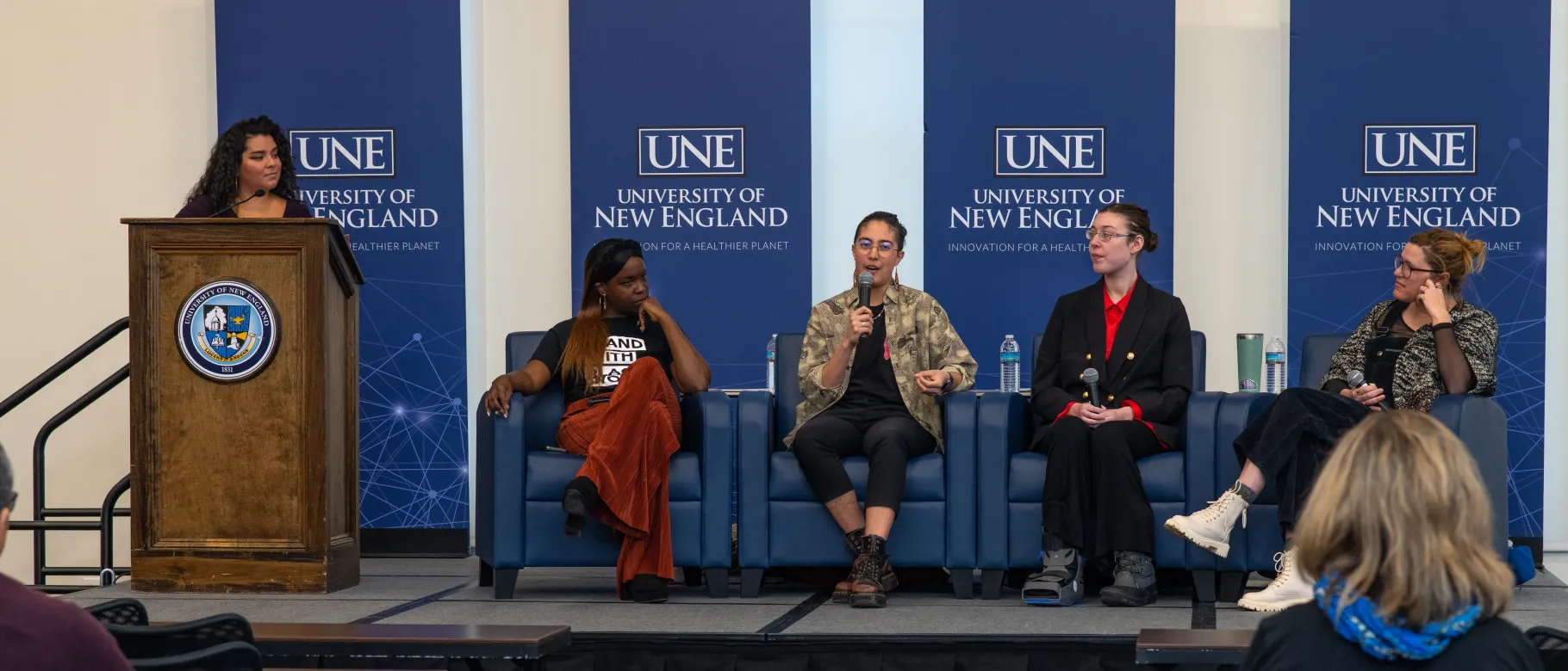 A group of panelists speaks onstage in the Harold Alfond Forum, discussing their approaches to local activism