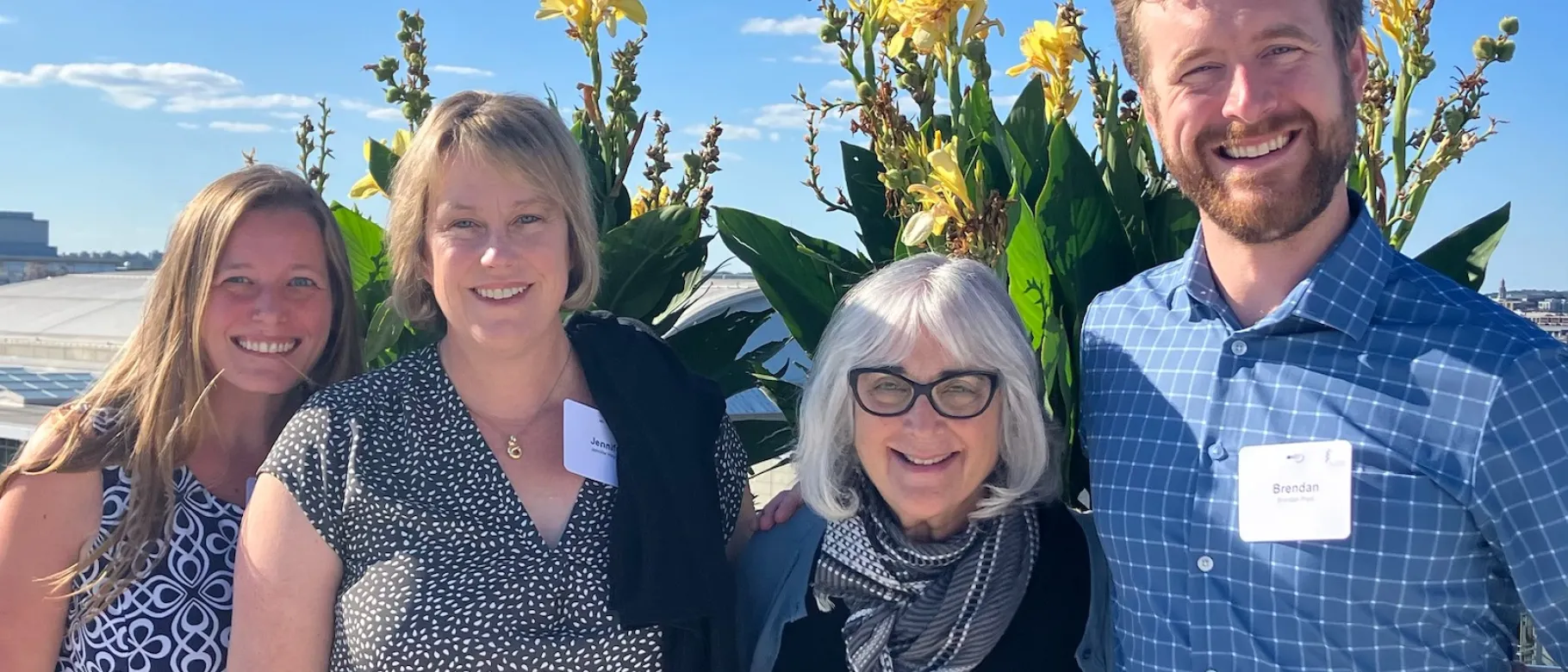 Four researchers pose in front of a flowers outside