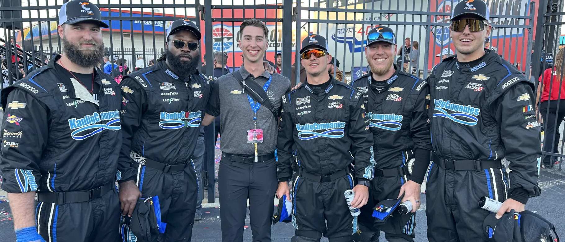 A UNE student poses with a group of race car drivers