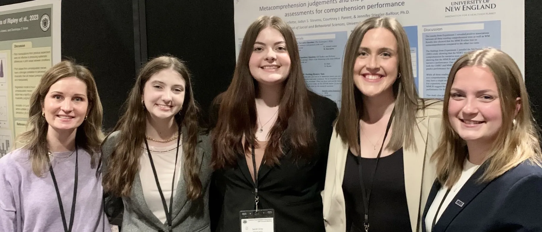 Four students and a professor pose in front of a research poster