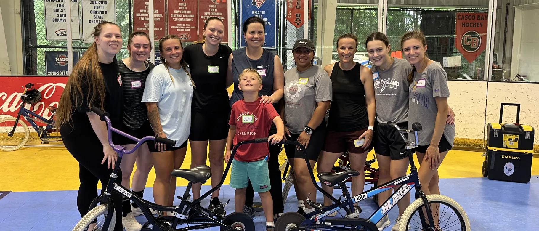 A group of UNE physical therapy students and faculty pose with a child surrounded by bikes 