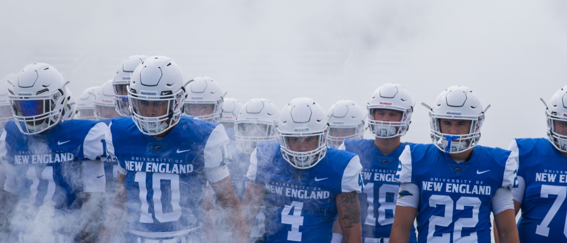 UNE football team members walk through the fog