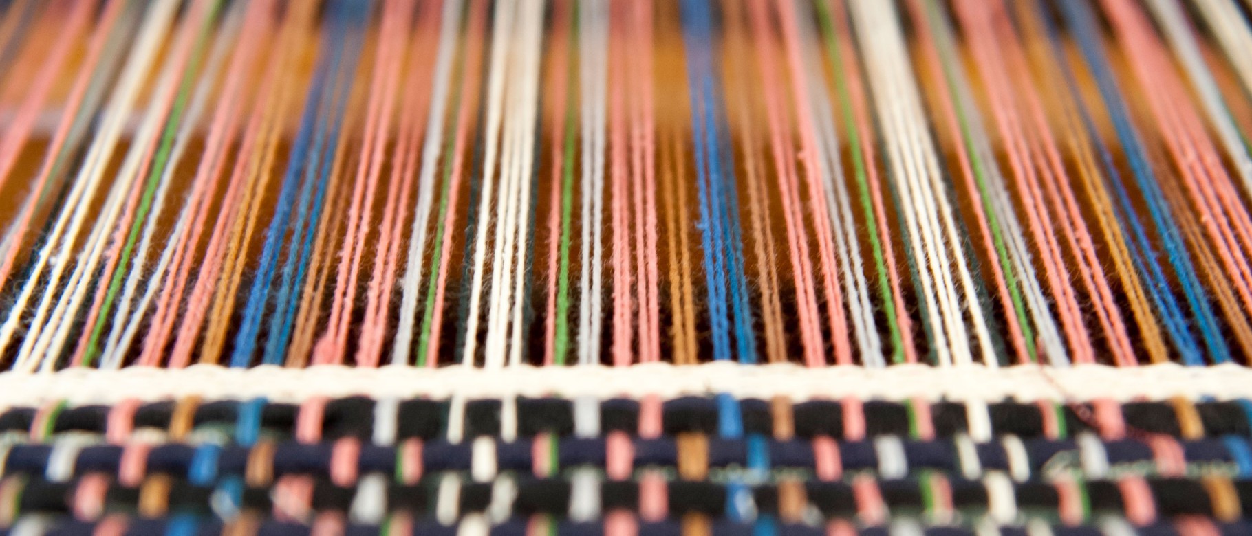 Spools of thread are shown along a loom 