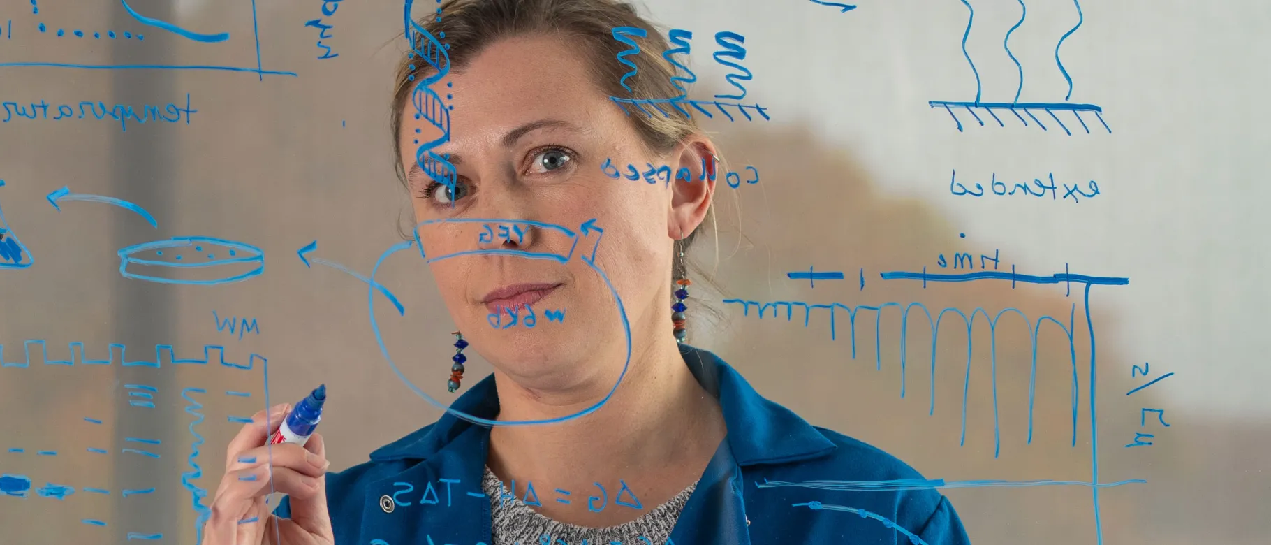 UNE's Eva Rose Balog writes down research notes on a clear whiteboard