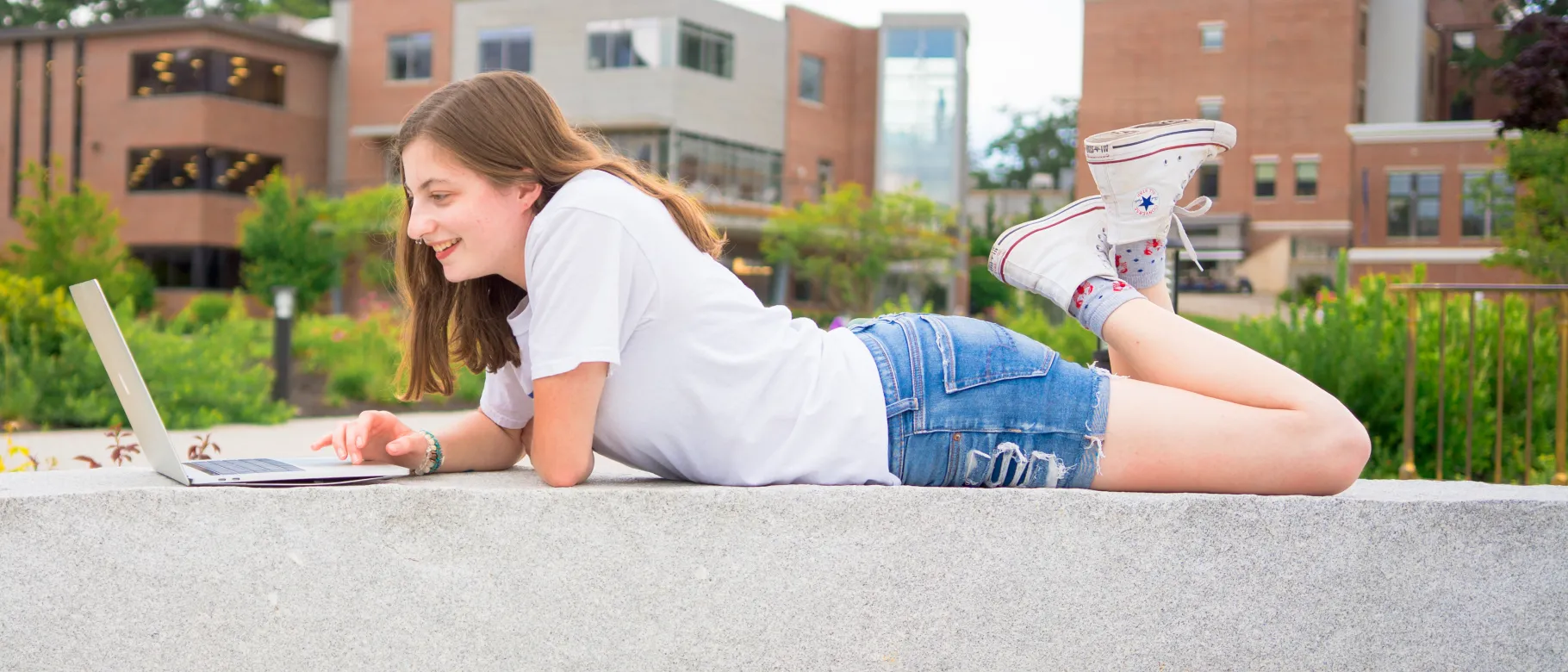 A UNE student works on her laptop outside the Danielle N. Ripich Commons