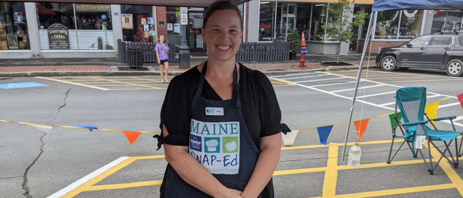 A woman stands at a booth in a Houlton, Maine park