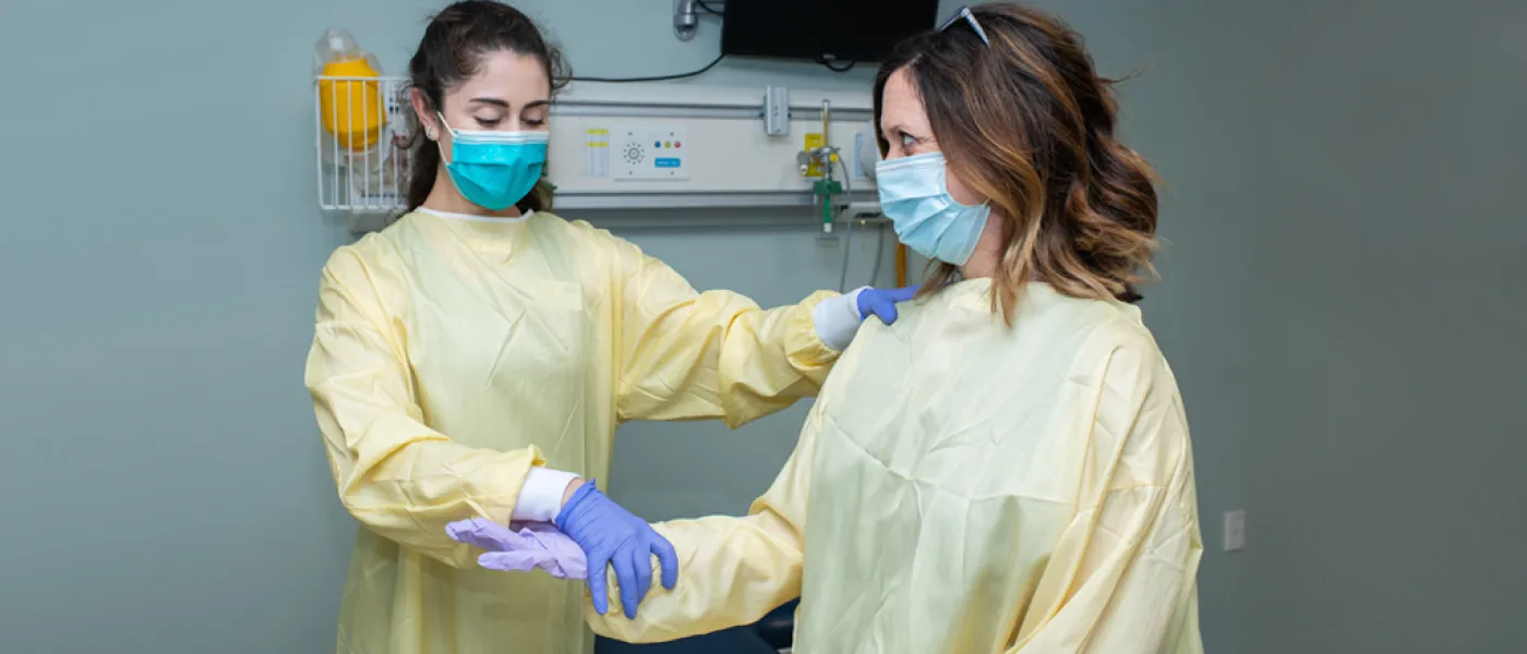 Two U N E students in surgical clothes work together