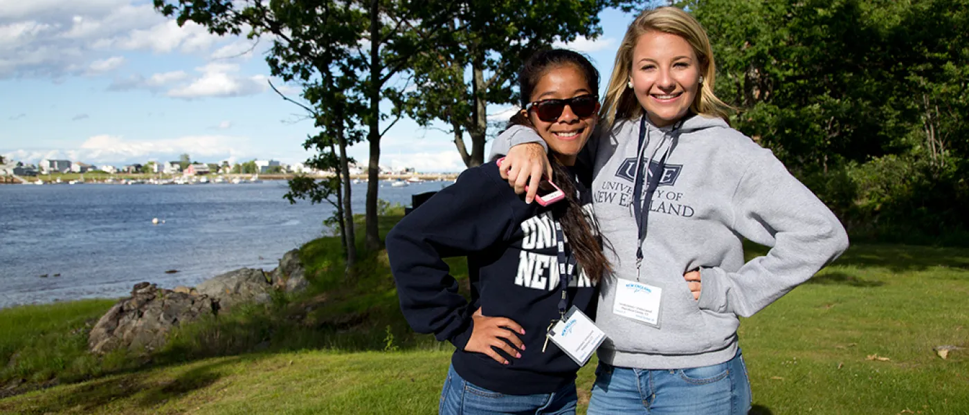 Two U N E students standing together by the water