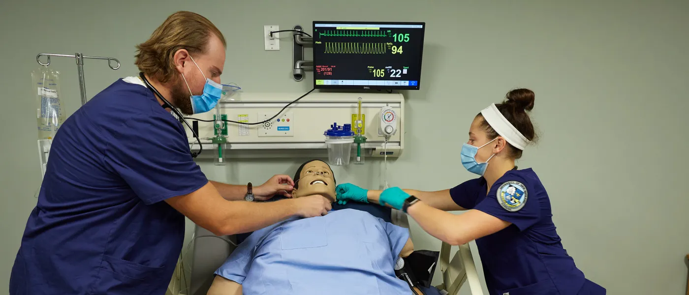 Two nursing students checking vitals on a dummy in the Simulation Lab