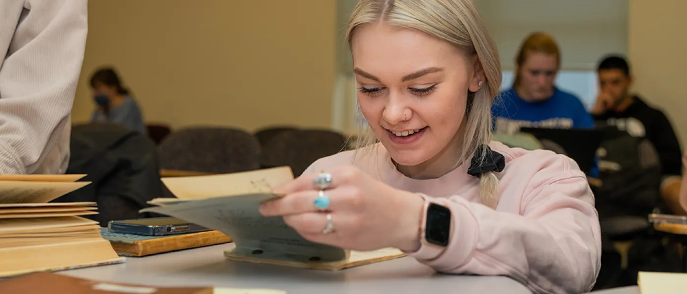 U N E student looking through historical paperwork