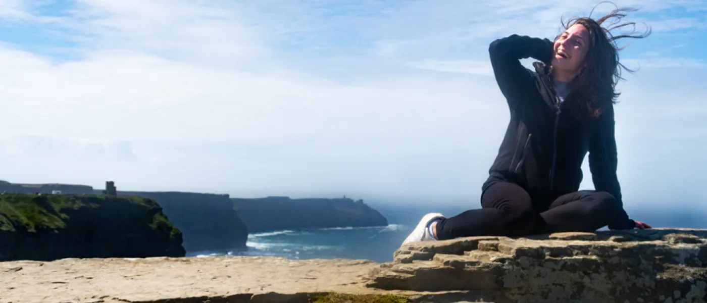 A student sits overlooking Ireland cliffs on the ocean