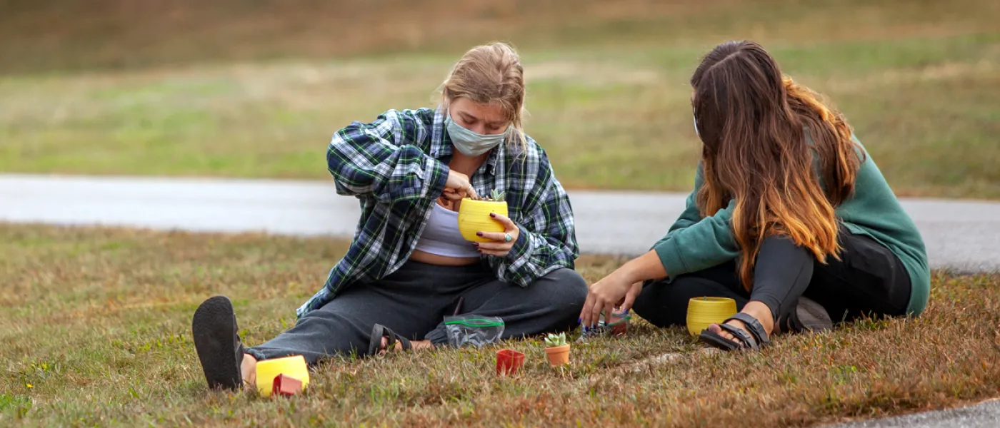 Two students planting succulents outside on the Biddeford Campus