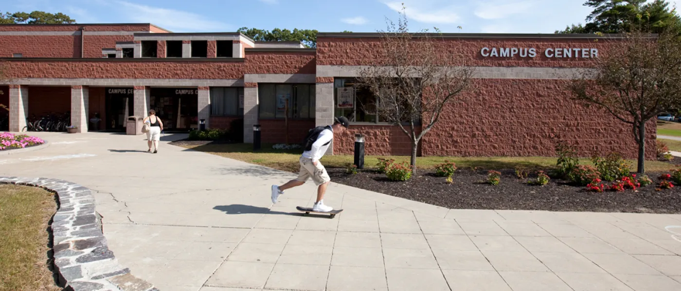 A student skateboards passed the Campus Center on the Biddeford Campus