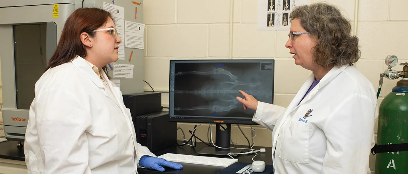 A student and professor review an X-ray on a monitor