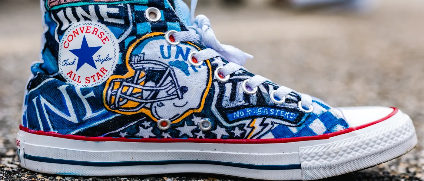 A Converse shoe is decked out in UNE logos and drawings