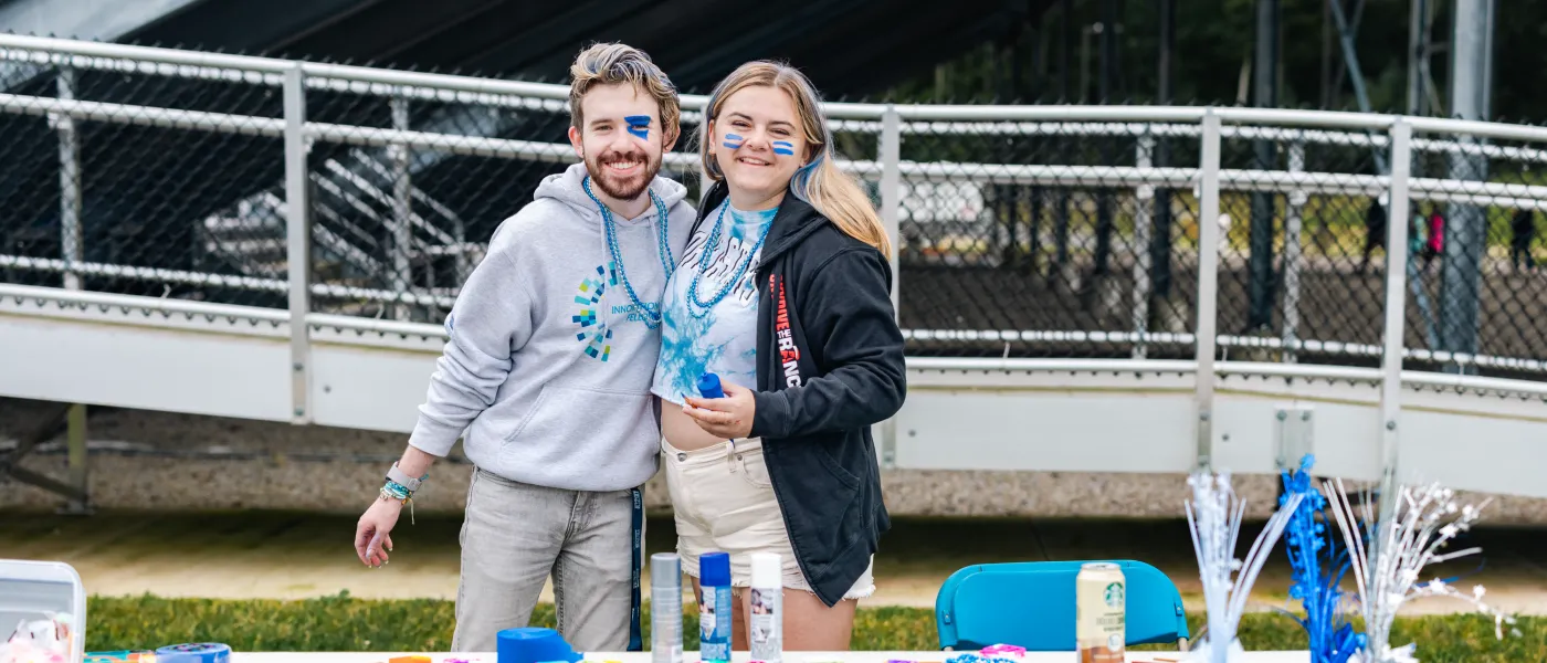 Two students pose at a merch table