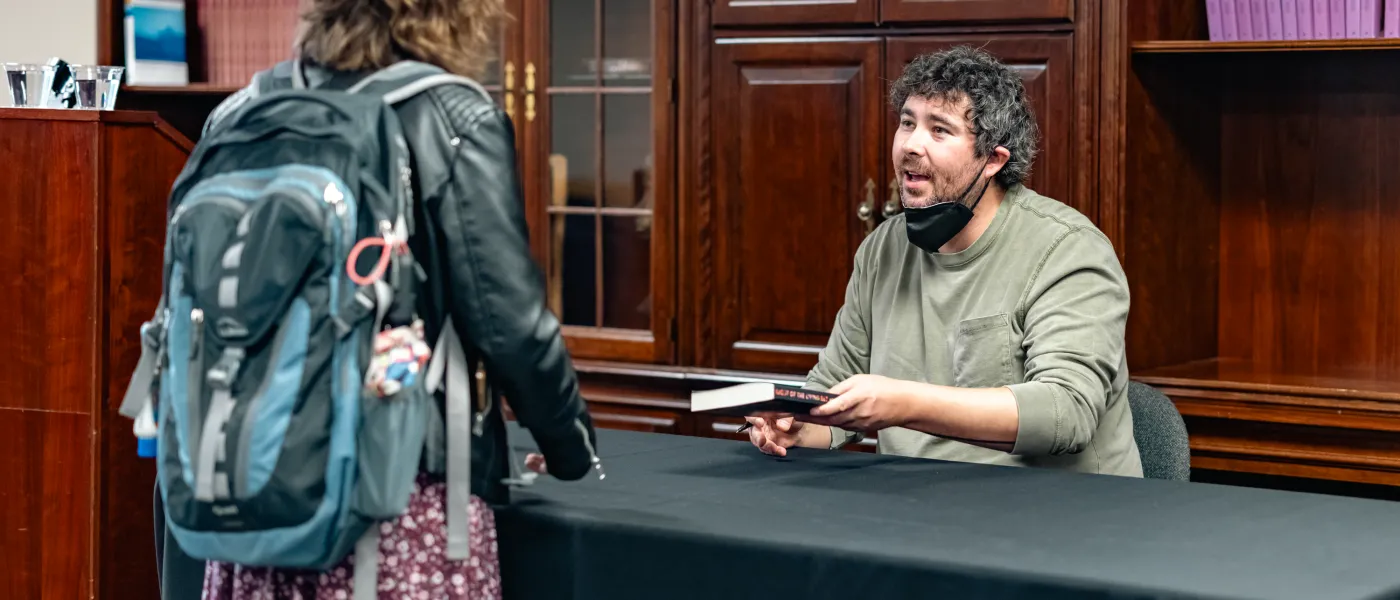 Morgan Talty signs a book for a student