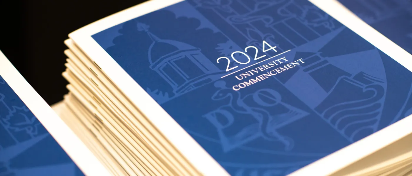 A stack of U N E 2024 commencement programs