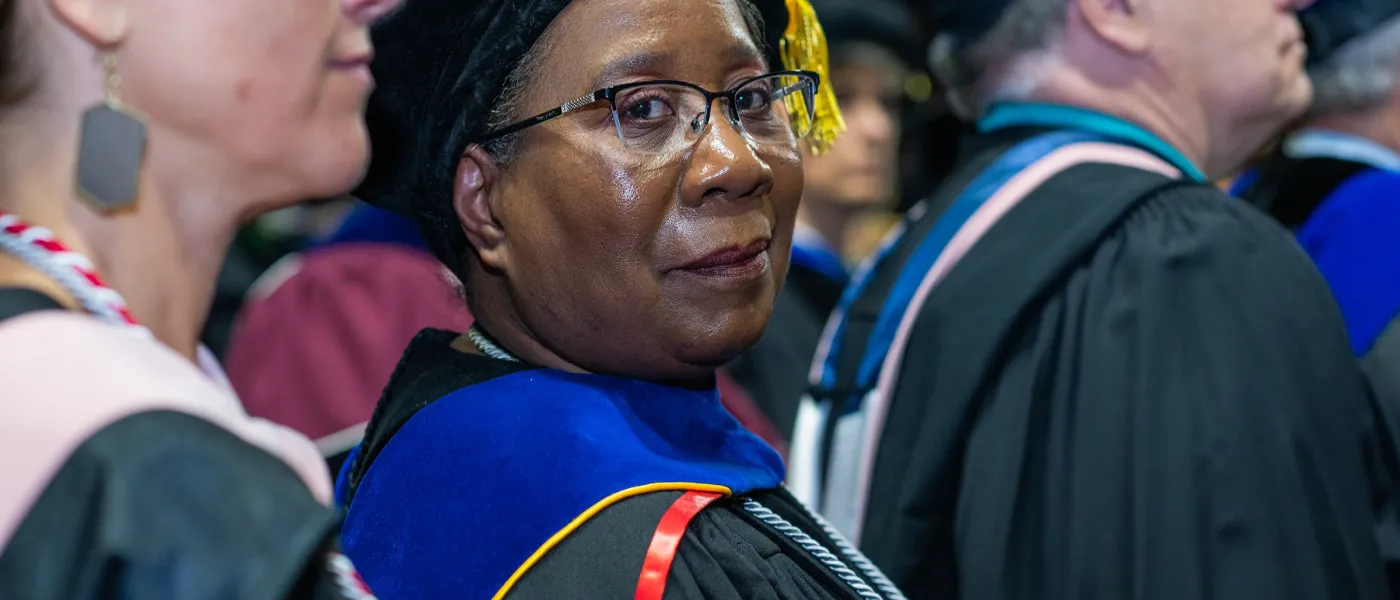 Carol J. Ewan Whyte, Ph.D., M.Sc. Director, U N E Graduate Programs in Public Health looks at the camera in a group of faculty at commencement