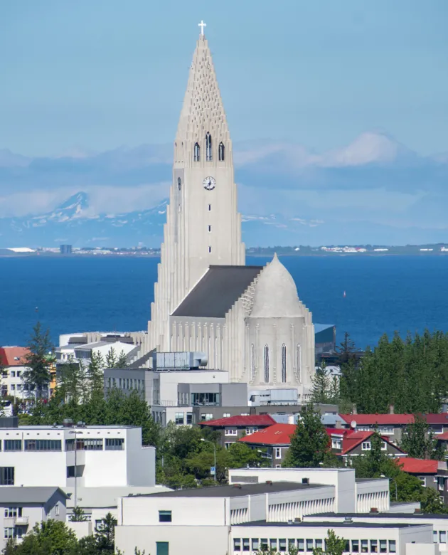 An icelandic church tower in front of an ocean and mountain backdrop