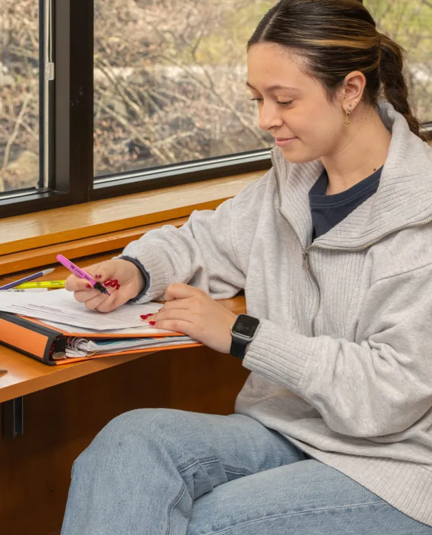 A student uses a pink highlighter on their notes