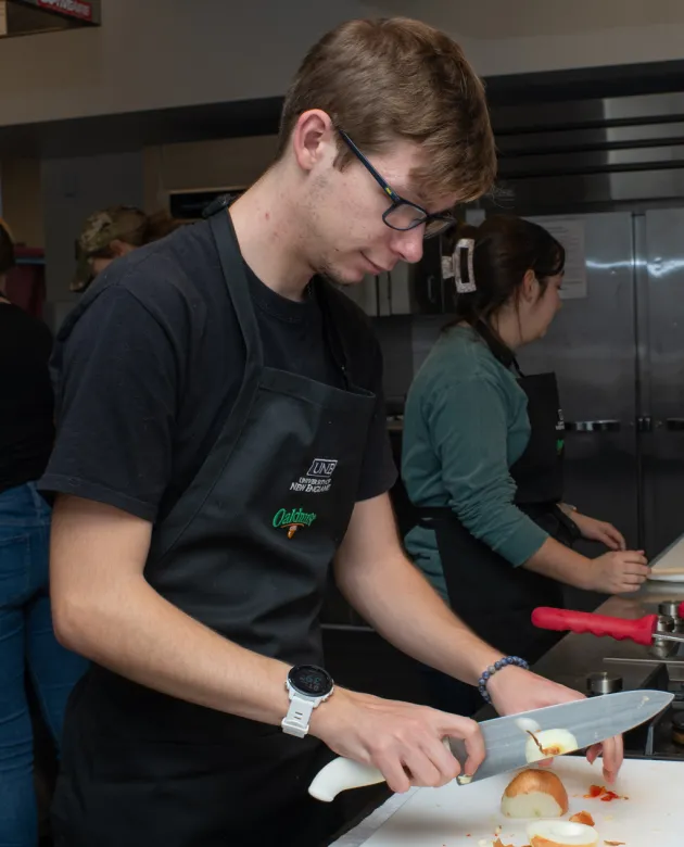 Nutrition students chop onions in the U N E class kitchen