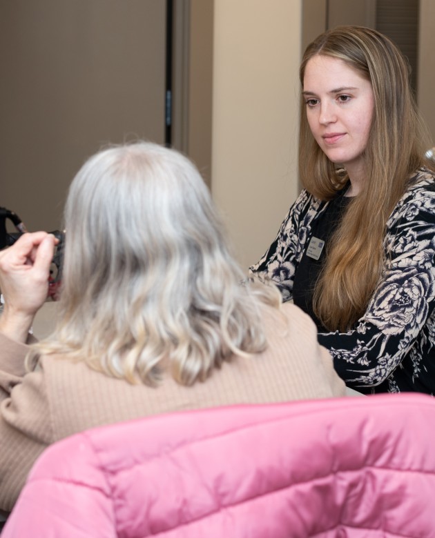 A social work student sits with an older woman at a C E A H event