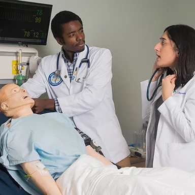 Two U N E Osteopathic Medicine students practicing on a dummy